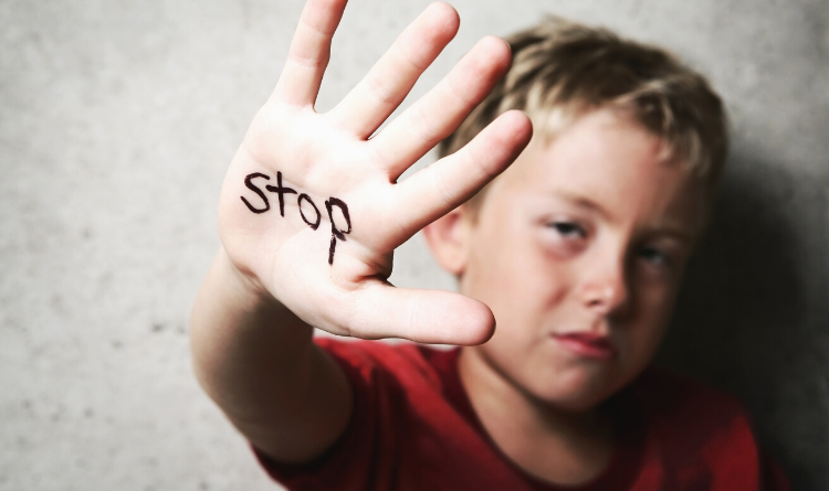 boy reaching up with the word stop on his hand