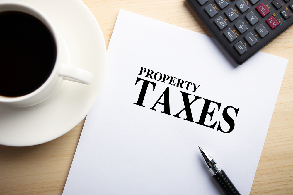 Property taxes on paper next to a cup of coffee and a black pen. 