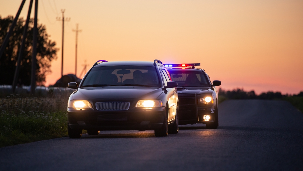 A car being pulled over by the police at sunset. 